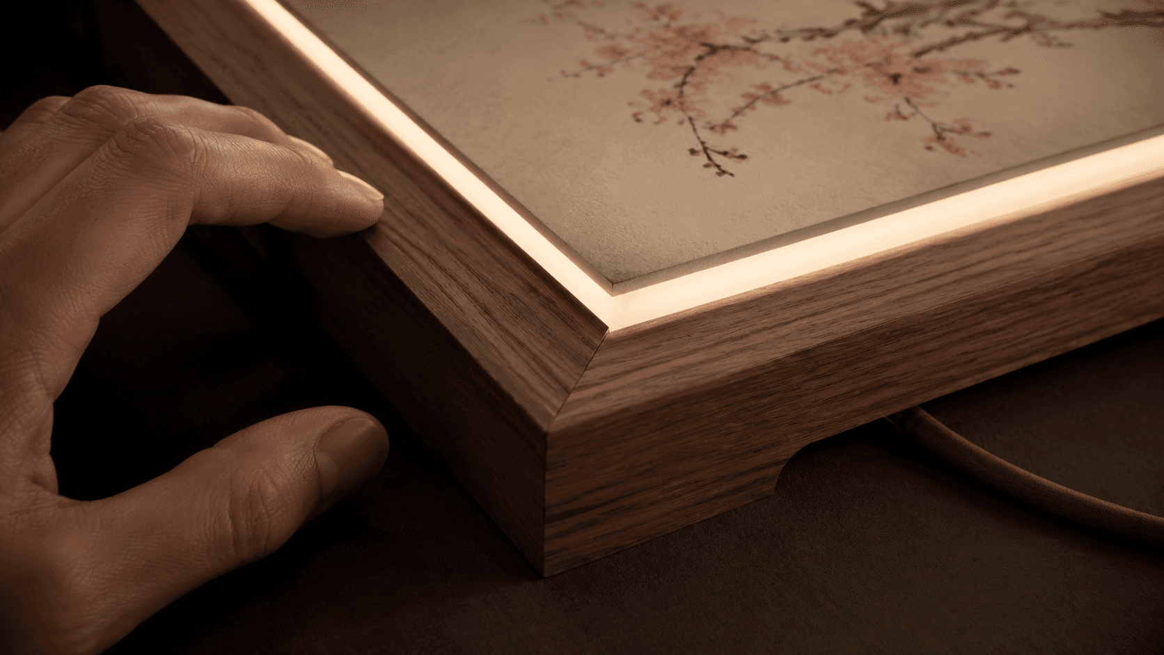 A hand inspecting the artwork finish and frame joint